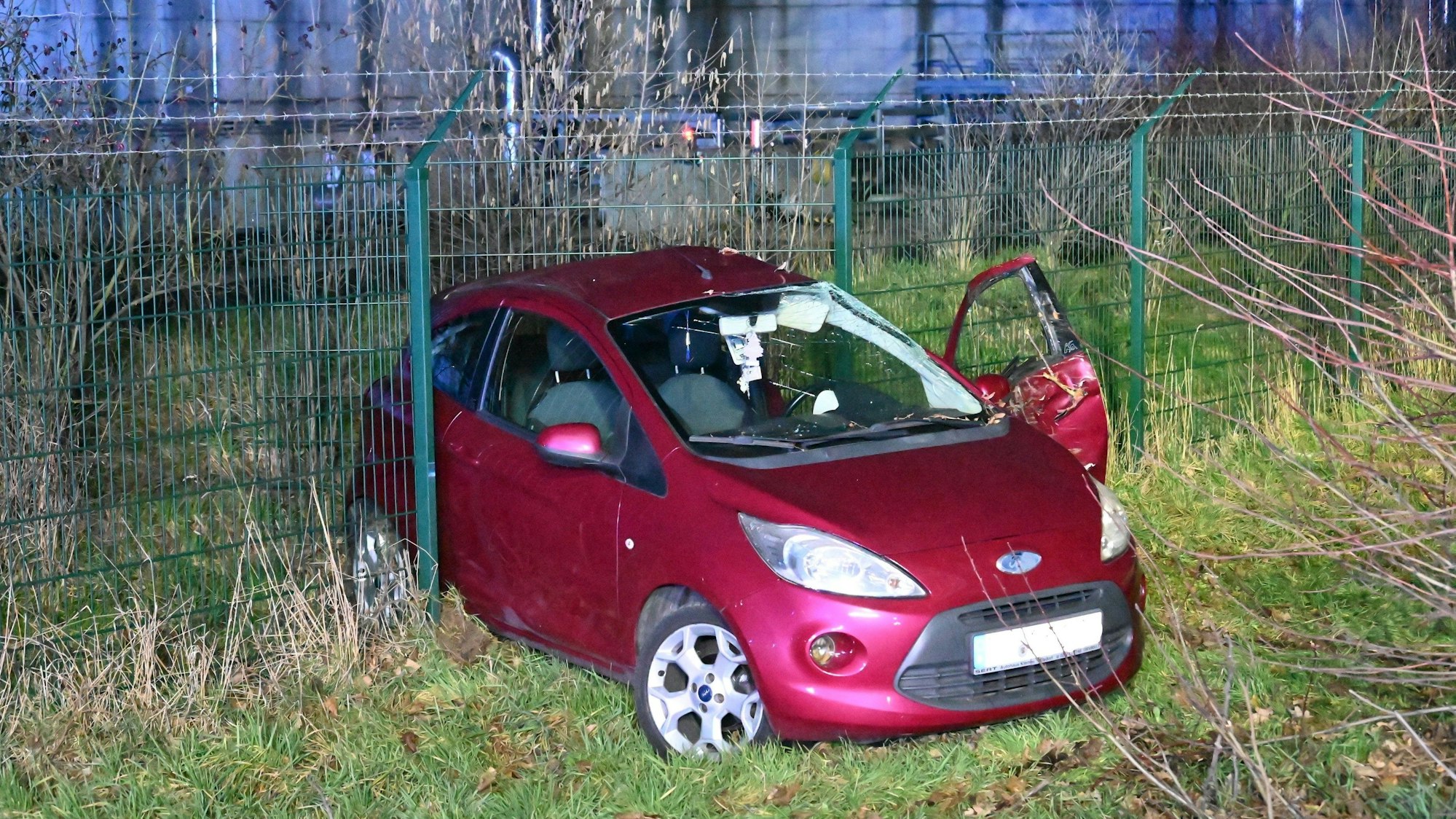 Ein roter Kleinwagen ist bei einem Unfall in den Zaun der Biogas-Anlage in Bergheim-Paffendorf gerutscht.