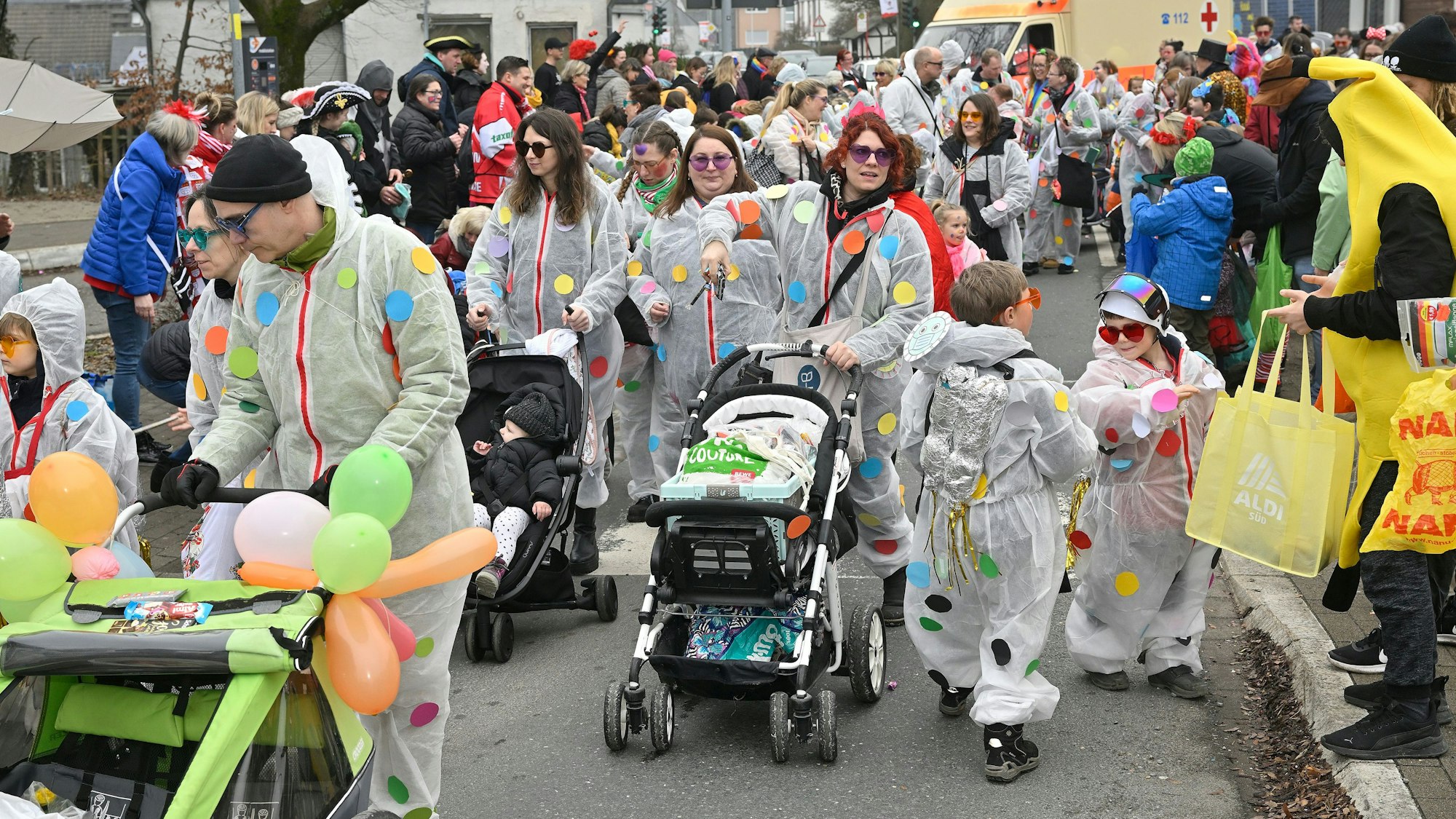 Eine Zuggruppe mit weißen Overalls, die mit bunten Punkten bedruckt sind.