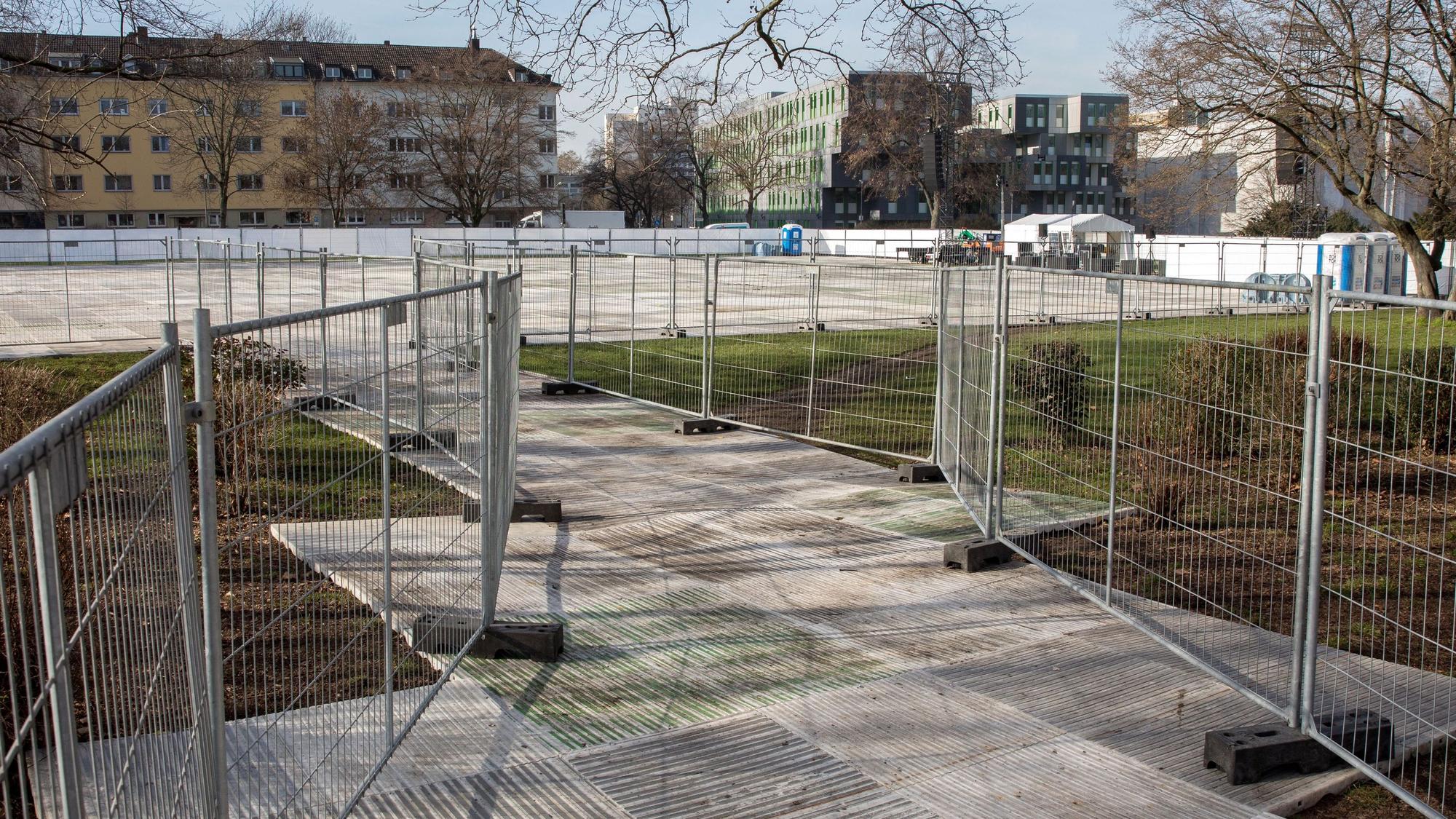 Der Blick von der Zülpicher Straße auf die Uniwiese lässt Bodenplatten und Absperrgitter erkennen, die zum Schutz der Wiese installiert wurden.
