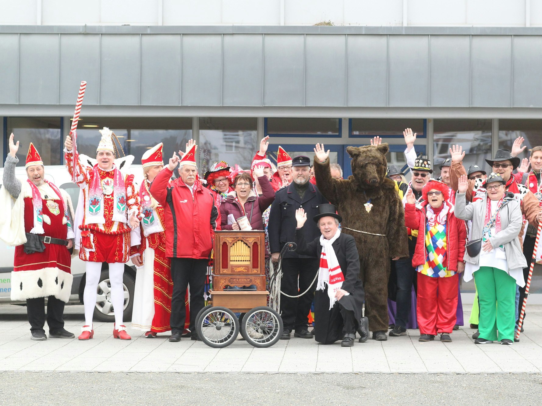 Ein Mann als Bär verkleidet und viele weiterw Kostümierte in den Farben rot und weiß winken in die Kamera.