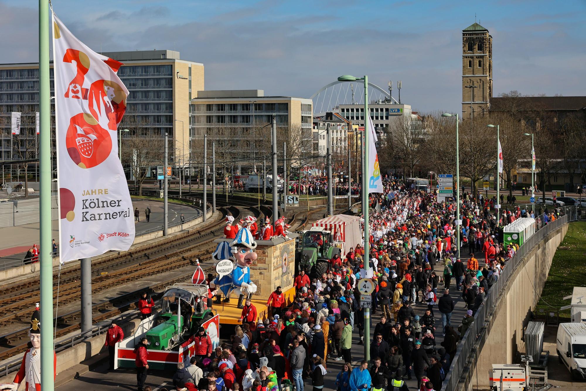 Wagen des Kölner Rosenmontagszugs überqueren die Deutzer Brücke Richtung Altstadt. Im Hintergrund ist die Skyline von Deutz zu sehen.