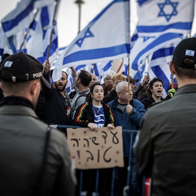 20.02.2023, Israel, Jerusalem: Demonstranten tragen israelische Fahnen während eines Protests