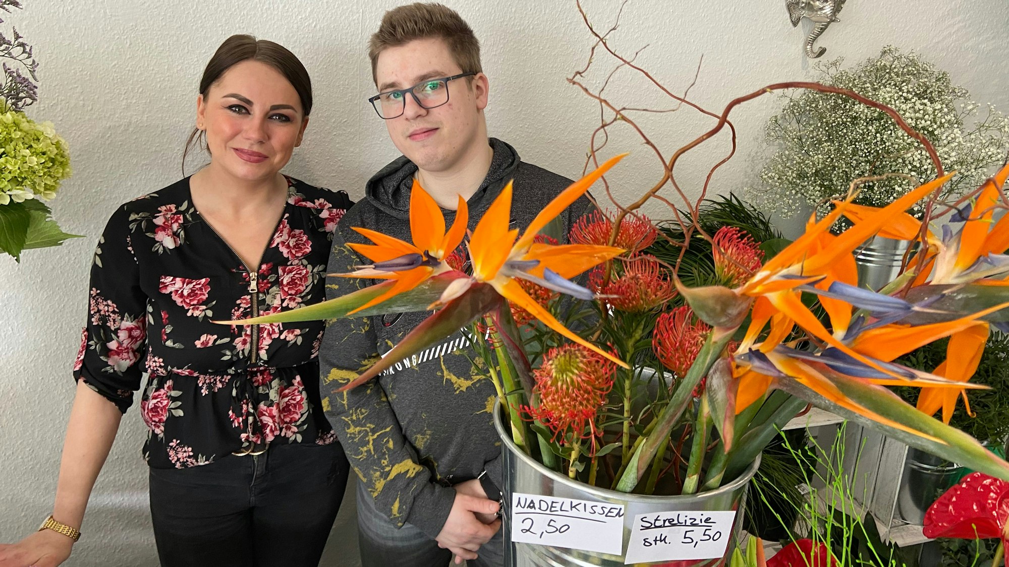 Auf dem Foto sind die Existenzgründer Joline Altstadt und Rafael Gassen zu sehen. Sie stehen inmitten bunter Blumen.