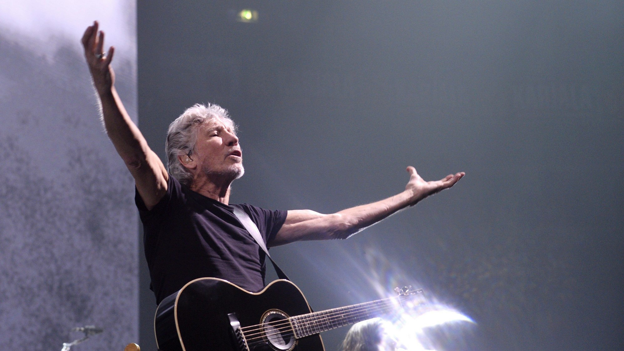 Das Bild zeigt den Musiker Rogr Waters mit einer Gitarre auf einer Bühne.