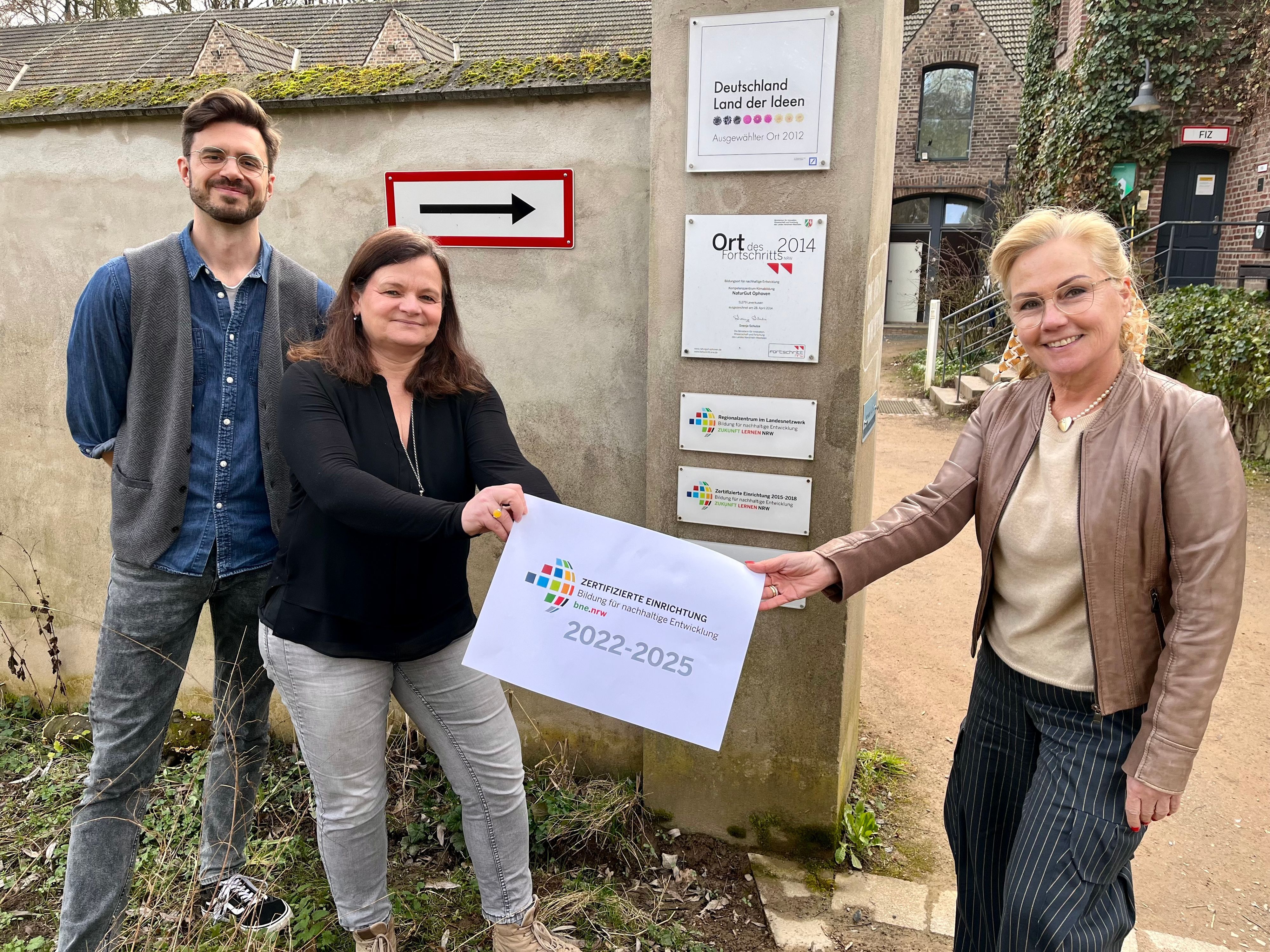 Lars Dietrich, Marianne Ackermann und Carolin Maus mit dem neuen Siegel vor dem Naturgut Ophoven.