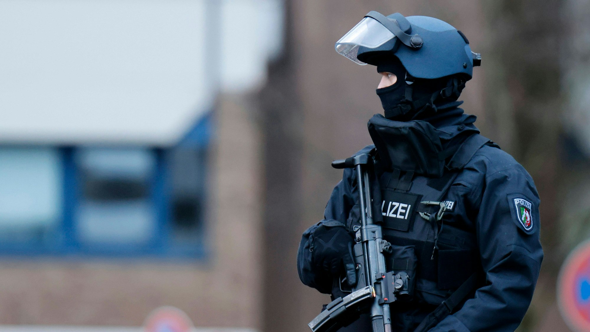 Ein Polizist mit Maschinenpistole bewacht die umliegenden Straßen, Dächer und Zufahrten.
