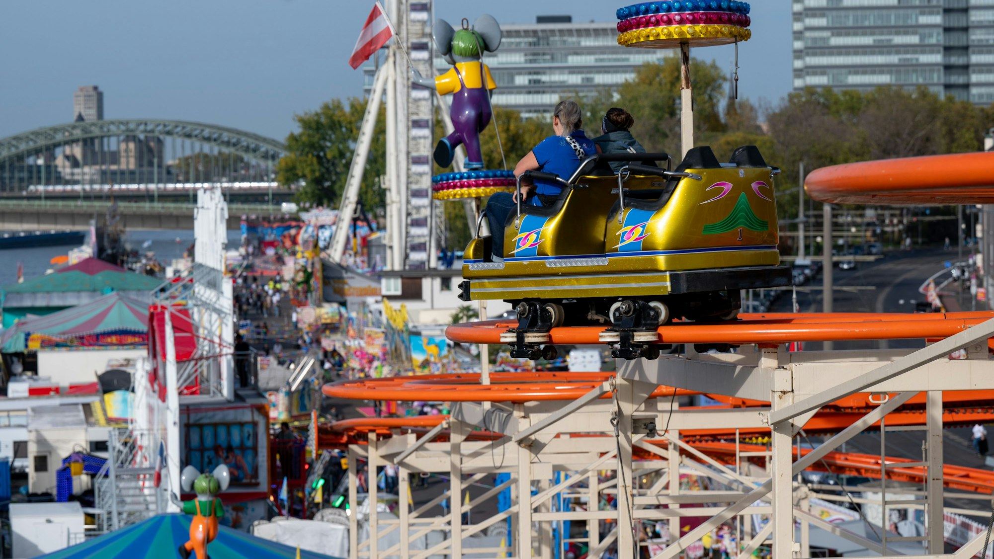 Eine Achterbahn auf der Deutzer Herbstkirmes mit zwei fahrenden Personen.