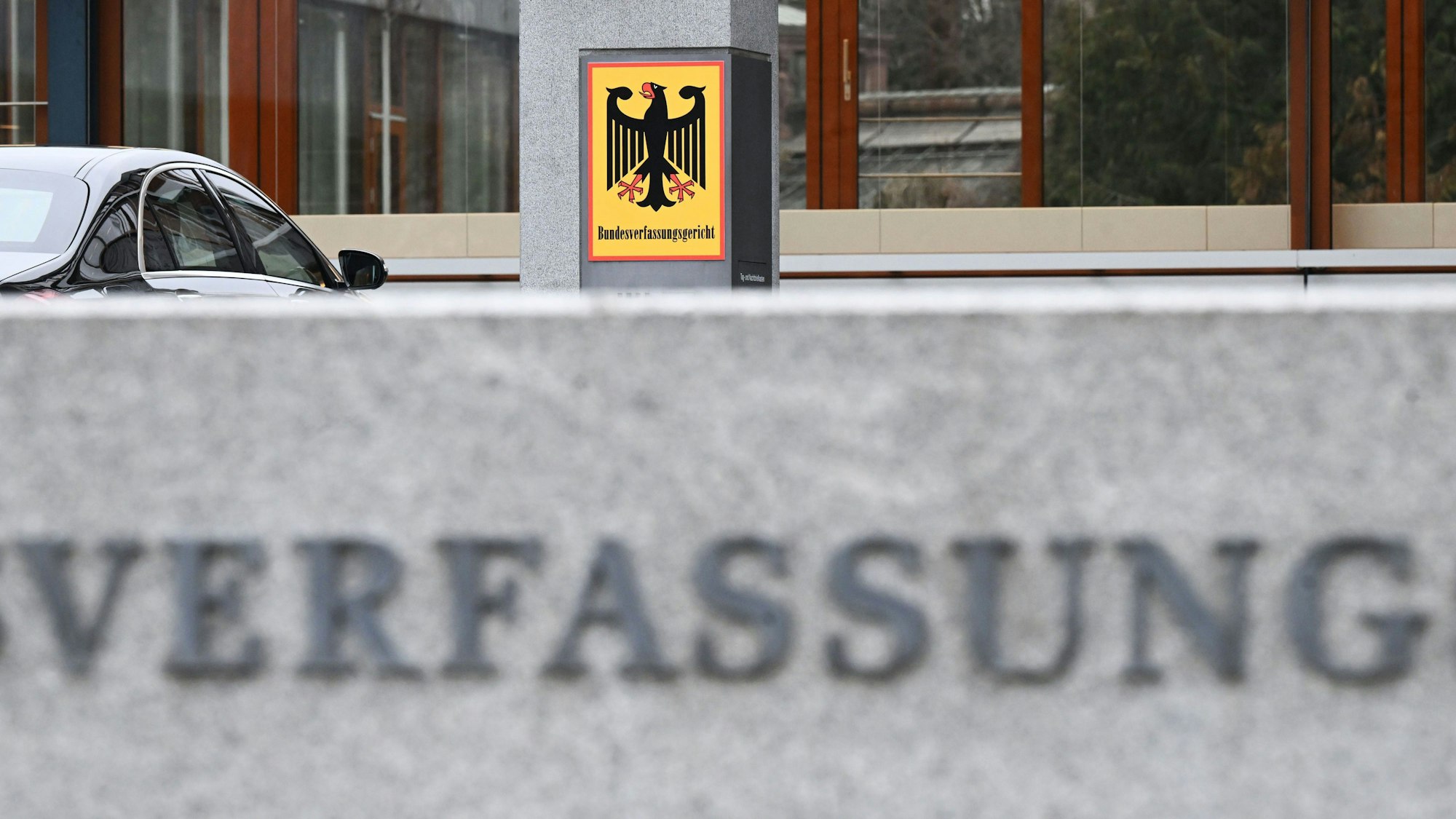 Ein Hinweisschild mit Bundesadler und dem Schriftzug Bundesverfassungsgericht ist vor dem Gericht zu sehen.