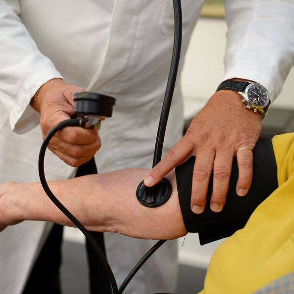 Ein Hausarzt misst in seiner Praxis einer Patientin den Blutdruck.