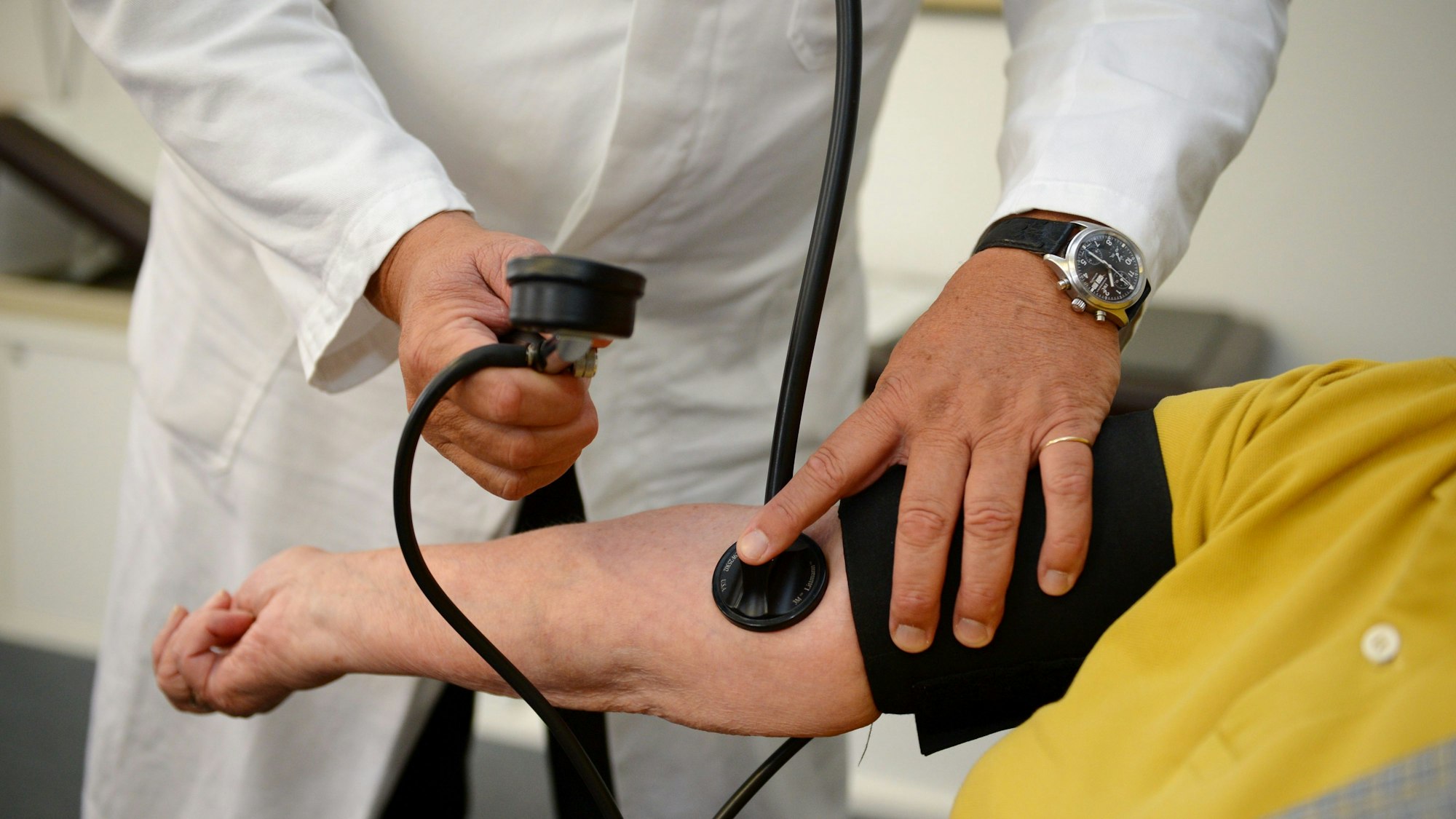 Ein Hausarzt misst in seiner Praxis einer Patientin den Blutdruck.
