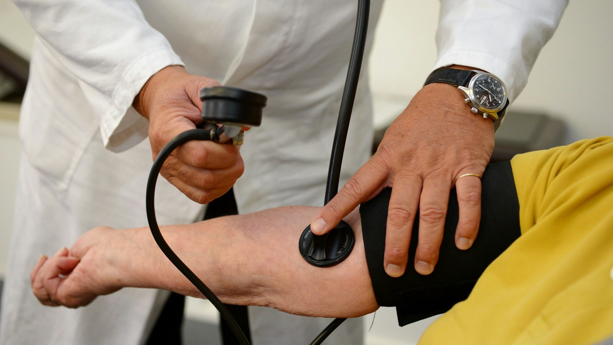 Ein Hausarzt misst in seiner Praxis einer Patientin den Blutdruck.