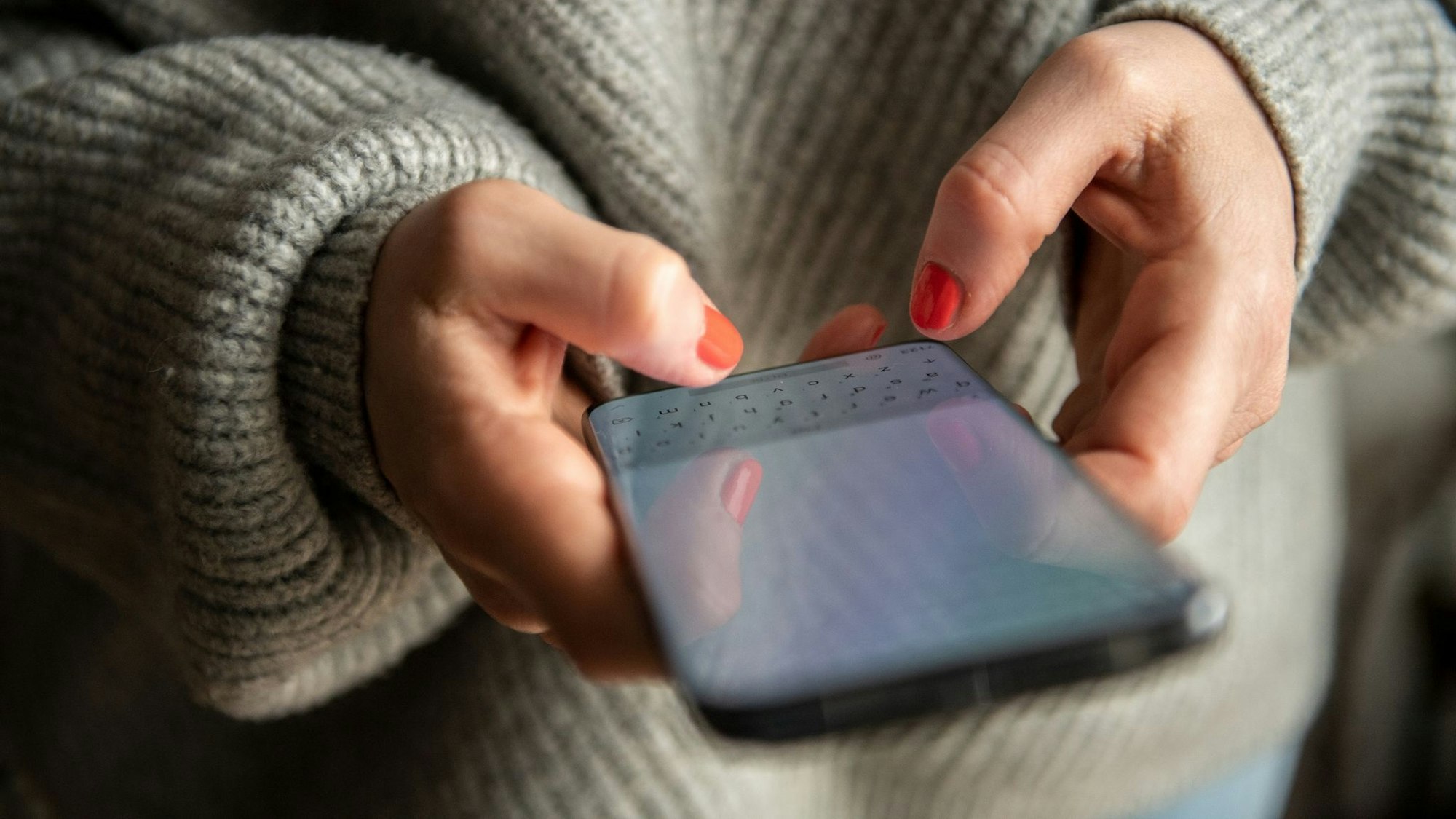 Eine Frau tippt auf ihrem Smartphone.