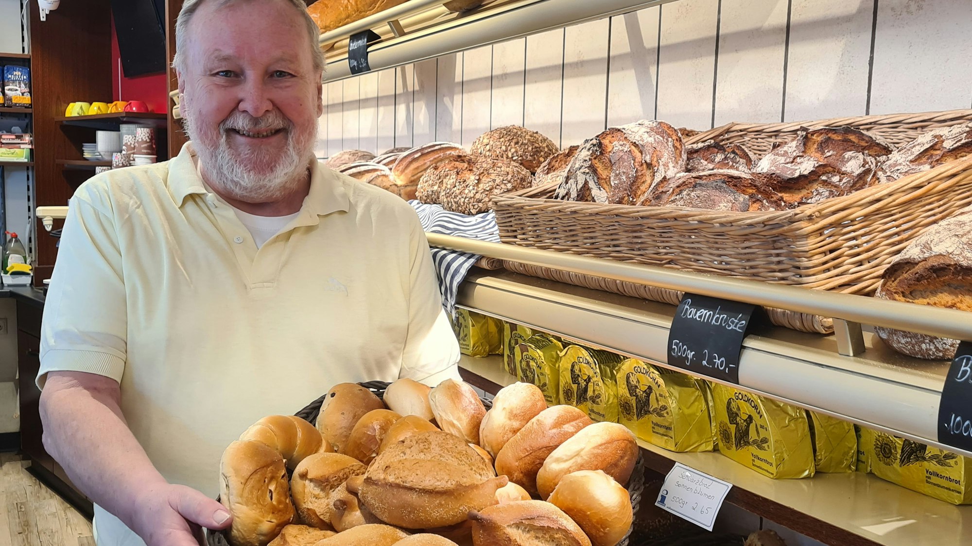 Das Foto zeigt Bäcker Willi Immerath. Er hält einen Korb frischer Brötchen in beiden Händen.