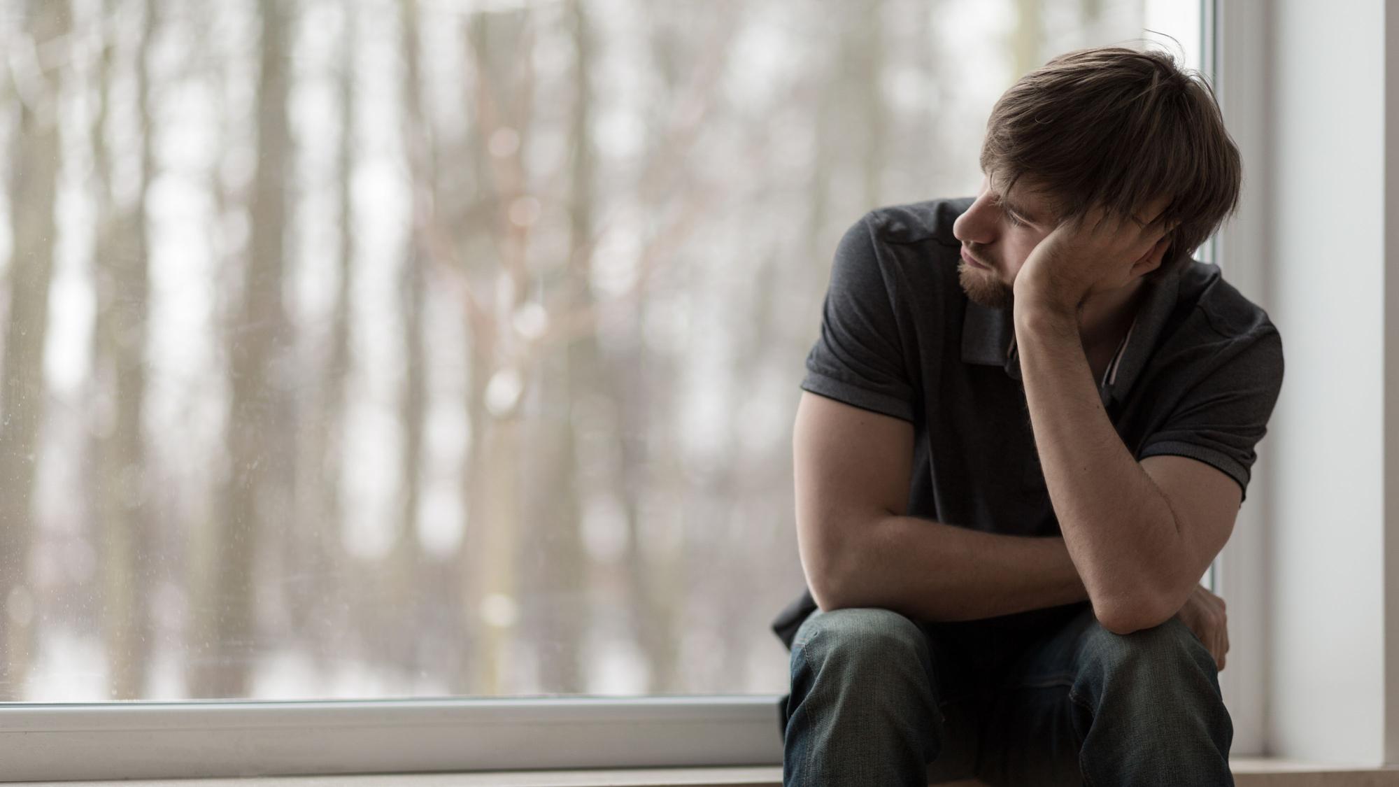 Ein Mann sitzt am Fenster und schaut nach draußen.