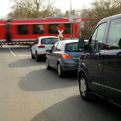 Vor dem Bahnübergang in Satzvey warten mehrere Autos, während ein Zug vorbeifährt.