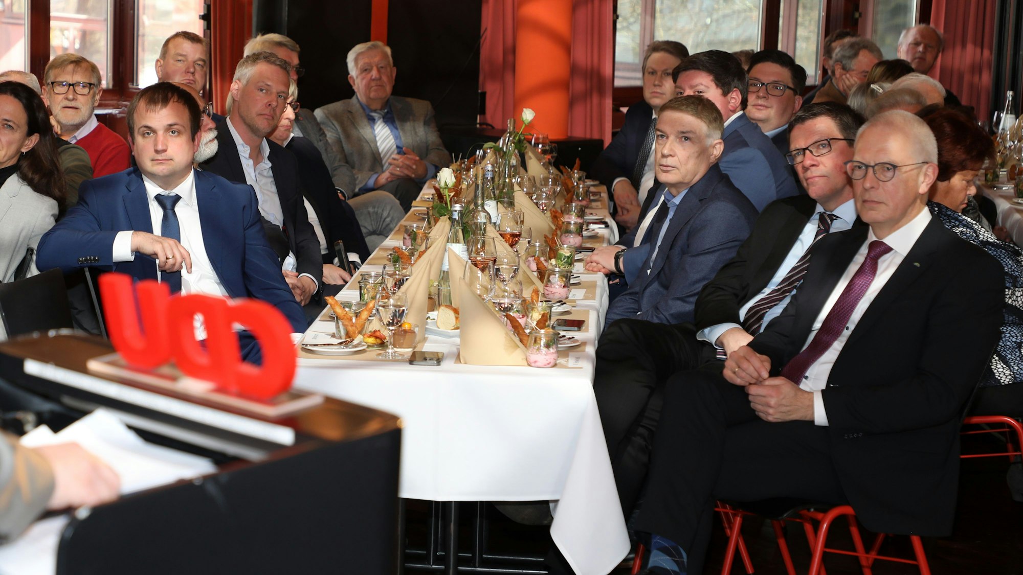 Menschen sitzen an gedeckten Tischen, im Vordergrund ist der Schriftzug CDU zu sehen.