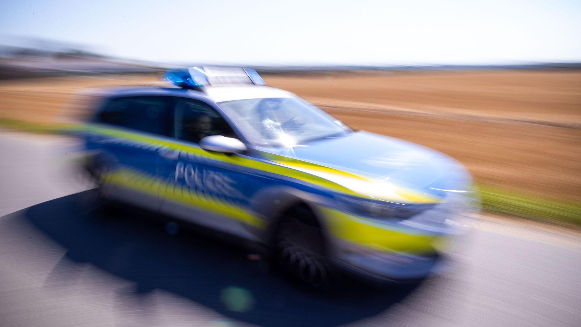 Ein Polizeiauto steht auf einer Straße vor einem Feld