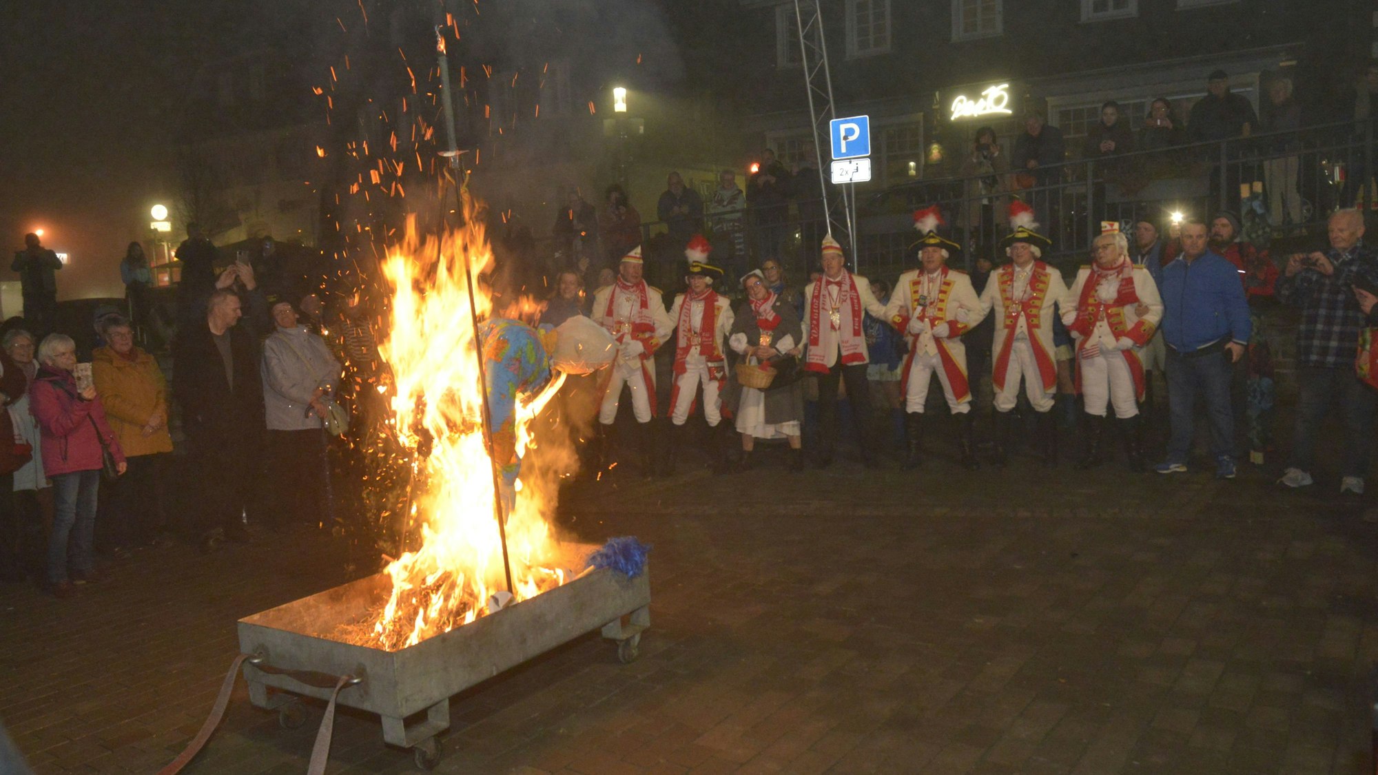 Es ist die Nubbelverbrennung auf dem Marktplatz mit Auskleiden des Dreigestirns zu sehen.
