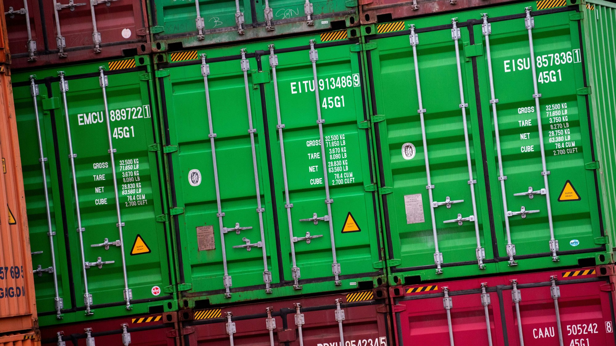 Container stehen auf einem Gelände im Hamburger Hafen gestapelt.