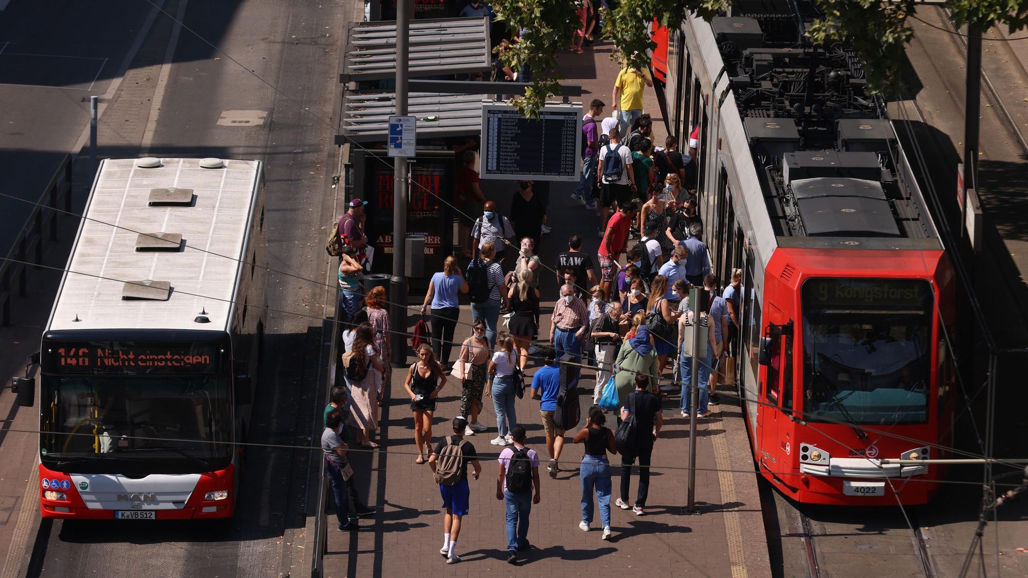 Zu sehen sind ein Bus, eine Stadtbahn und mehrere Menschen an der oberirdischen KVB-Haltestelle am Neumarkt.