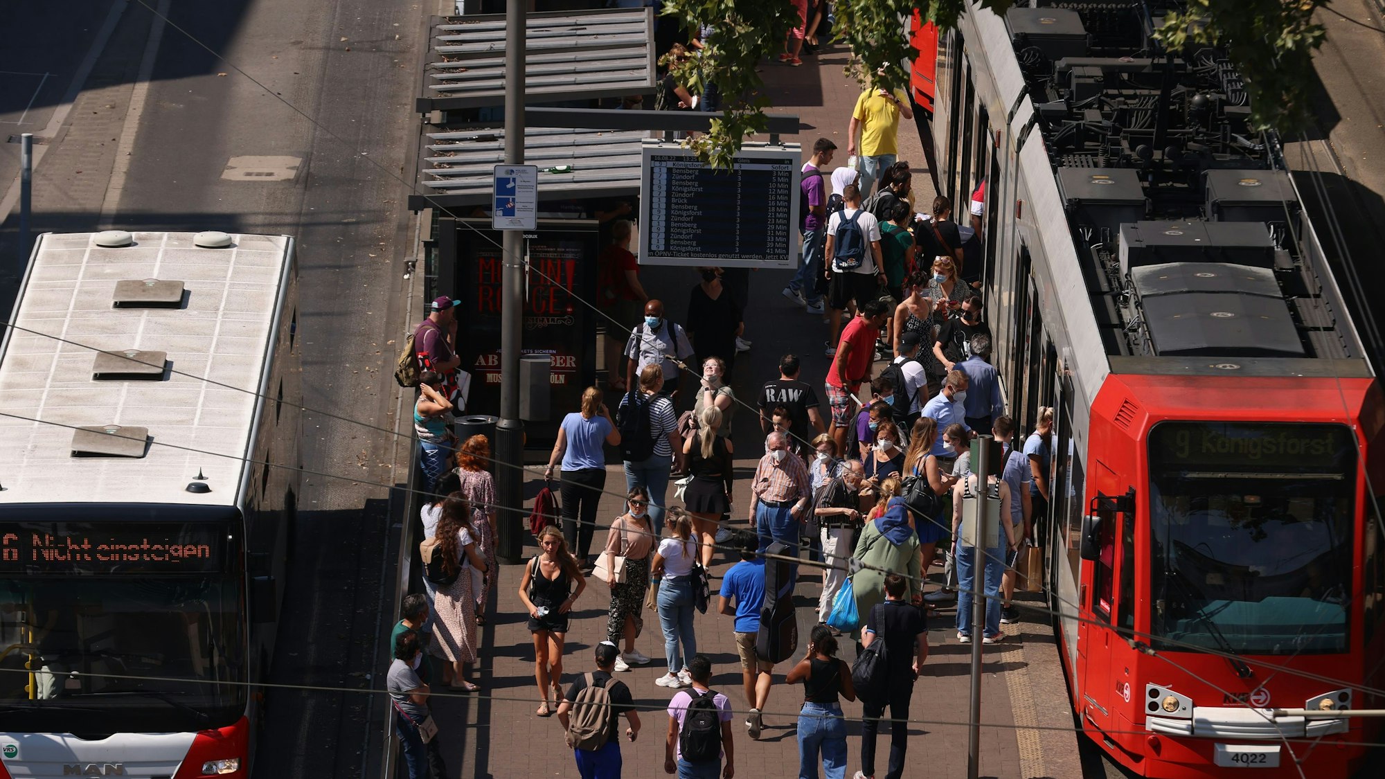 Zu sehen sind eine Stadtbahn und ein Bus der KVB sowie eine große Menschenansammlung am Kölner Neumarkt.