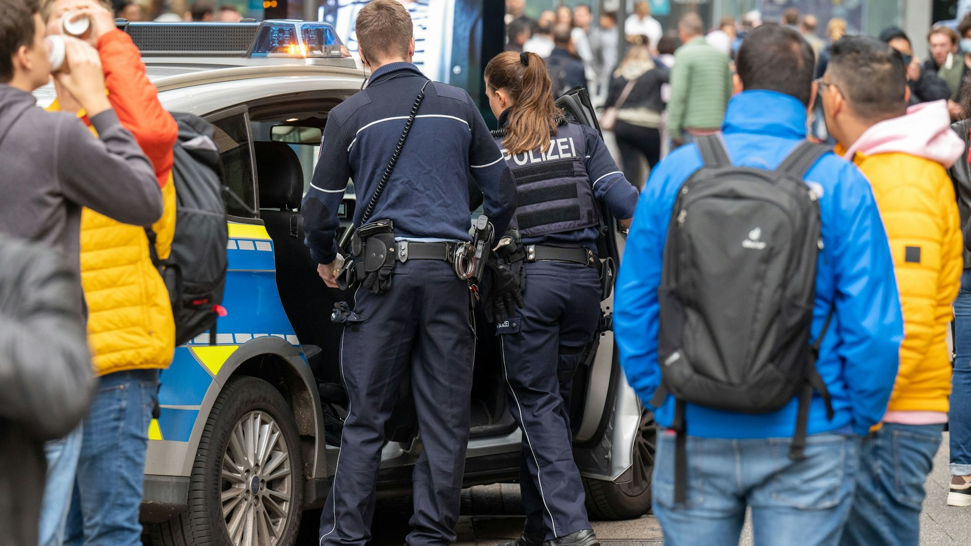 Polizeibeamte bei einem Einsatz an ihrem Streifenwagen.