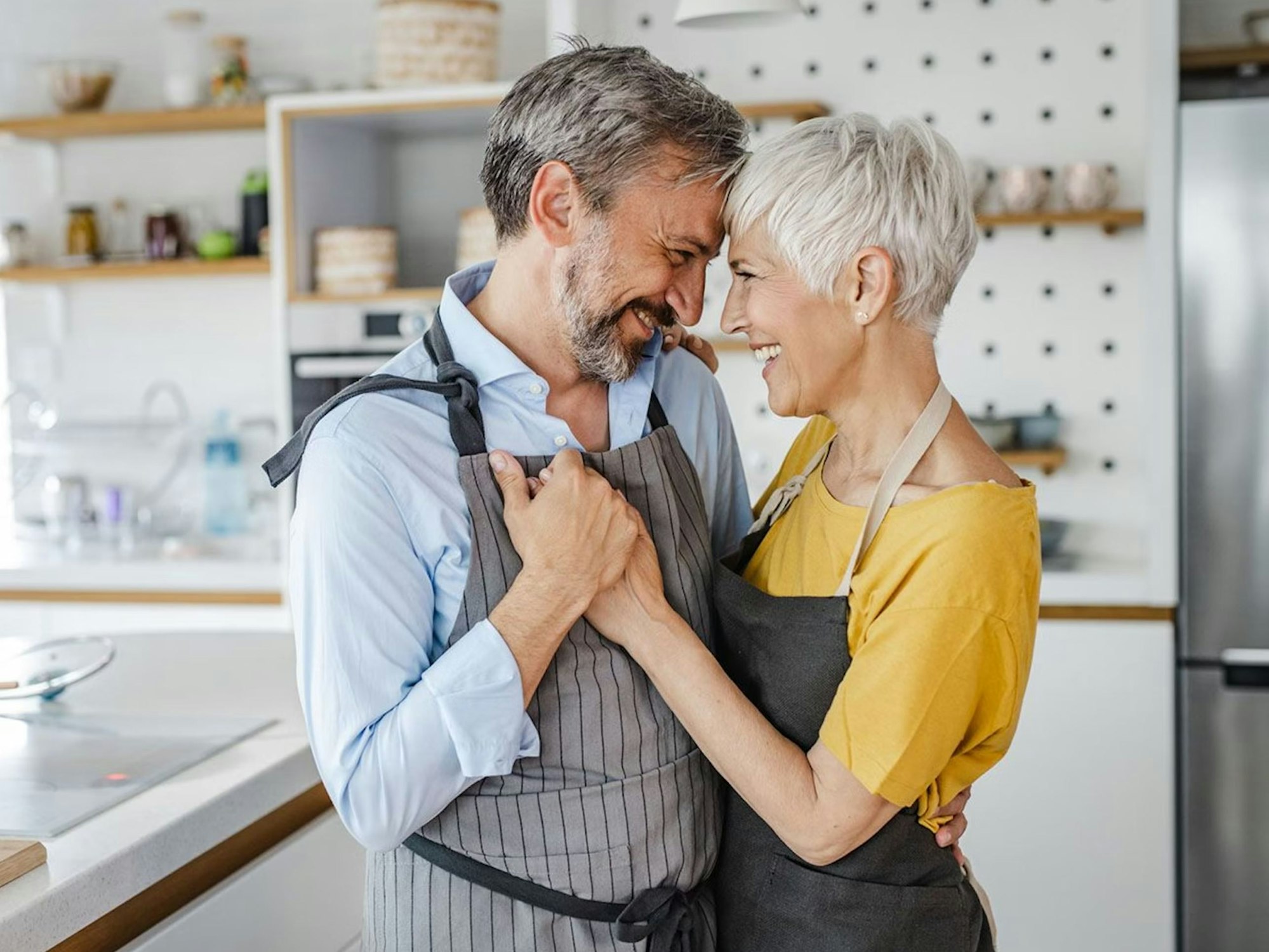 Reifes Paar tanzt verliebt in der Küche. Bild zum Partnersuche ab 50 Artikel.