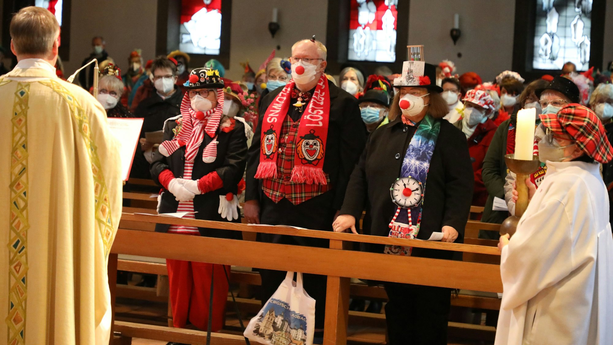Kostümierte Menschen stehen in den Kirchenbänken von Herz Jesu Schildgen.