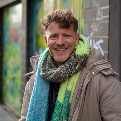 Max von Einem in Winterjacke und Schal lacht in die Kamera.