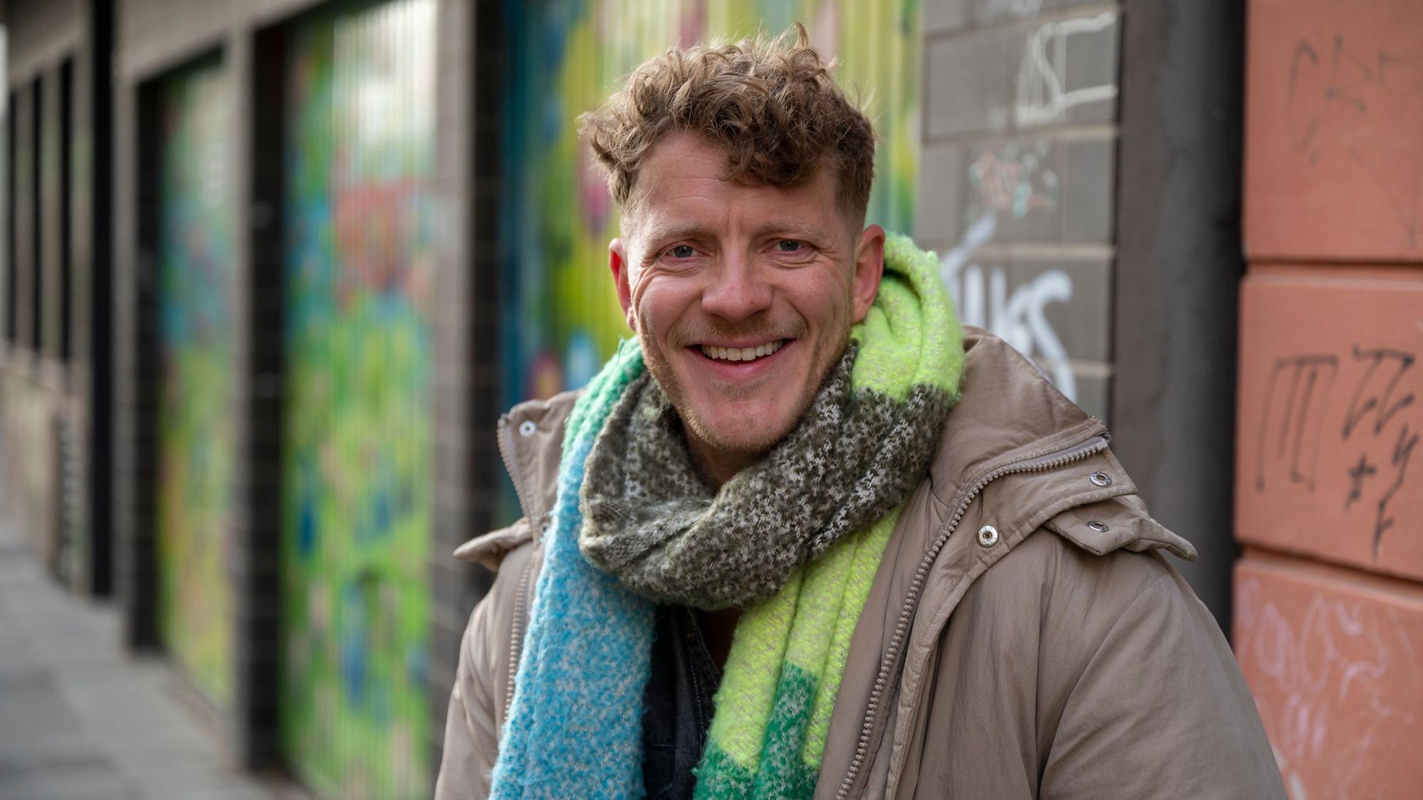 Max von Einem in Winterjacke und Schal lacht in die Kamera.
