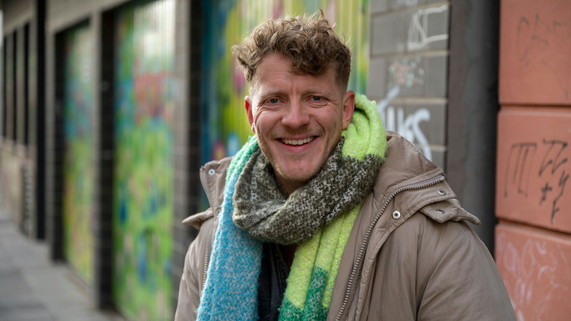 Max von Einem in Winterjacke und Schal lacht in die Kamera.