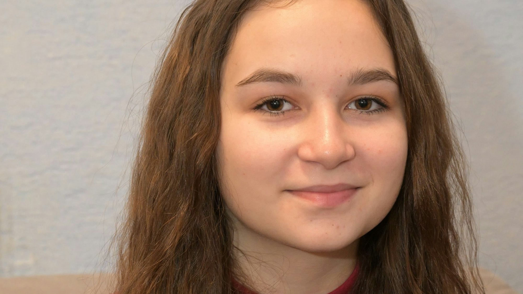 Sabina Berdo sitzt auf einer Couch und schaut in die Kamera.