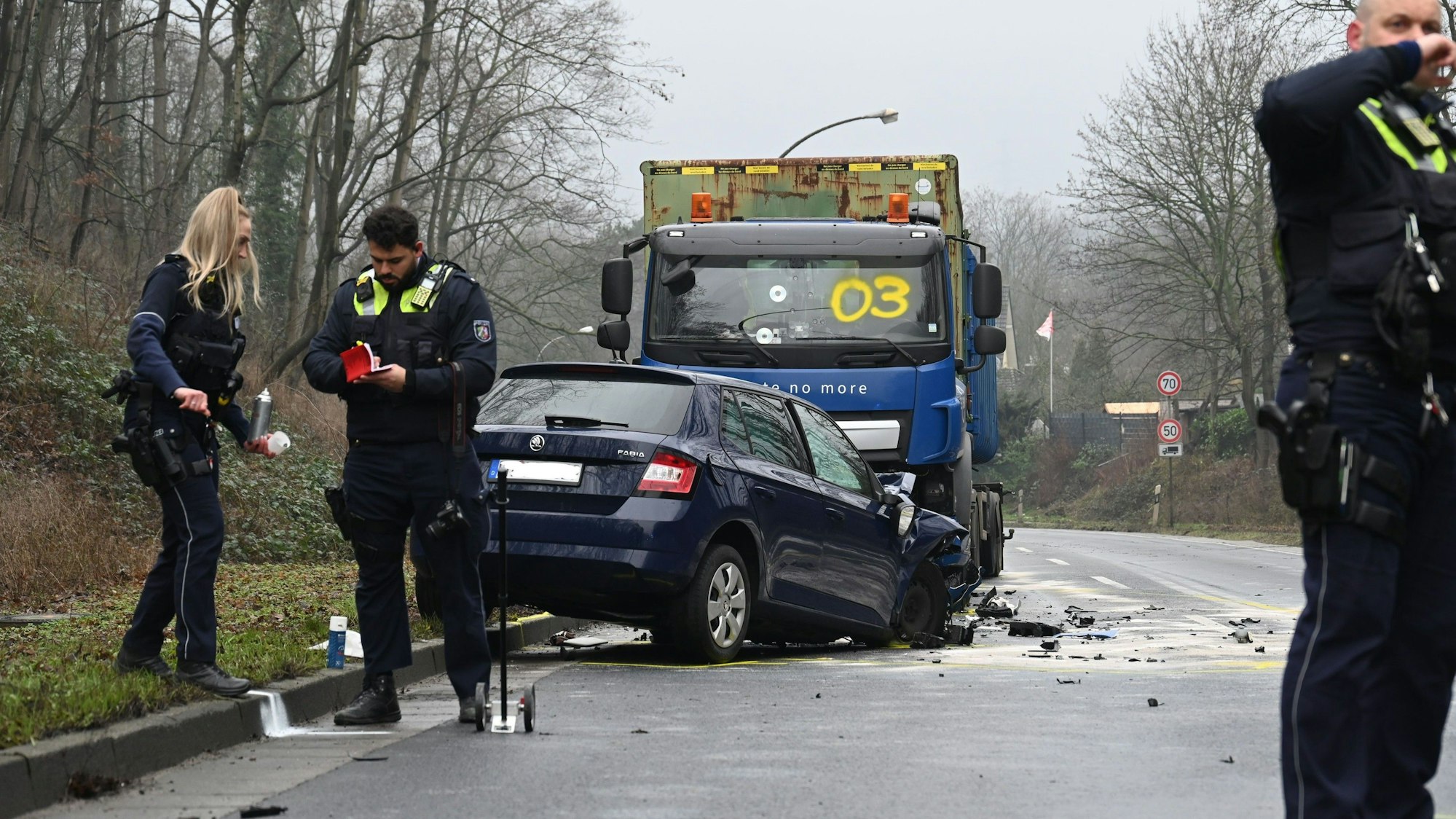 Ein demolierter Pkw und ein Lkw stehen auf der Straße, drumherum Polizistinnen und Polizisten.