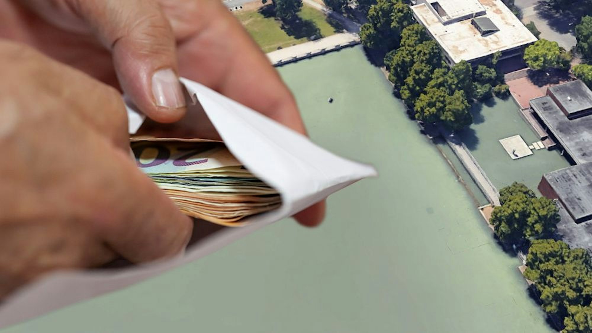 Der Aachener Weiher mit der kleinen Brücke im Hintergrund, im Vordergrund Hände, die einen Umschlag mit Geld halten
