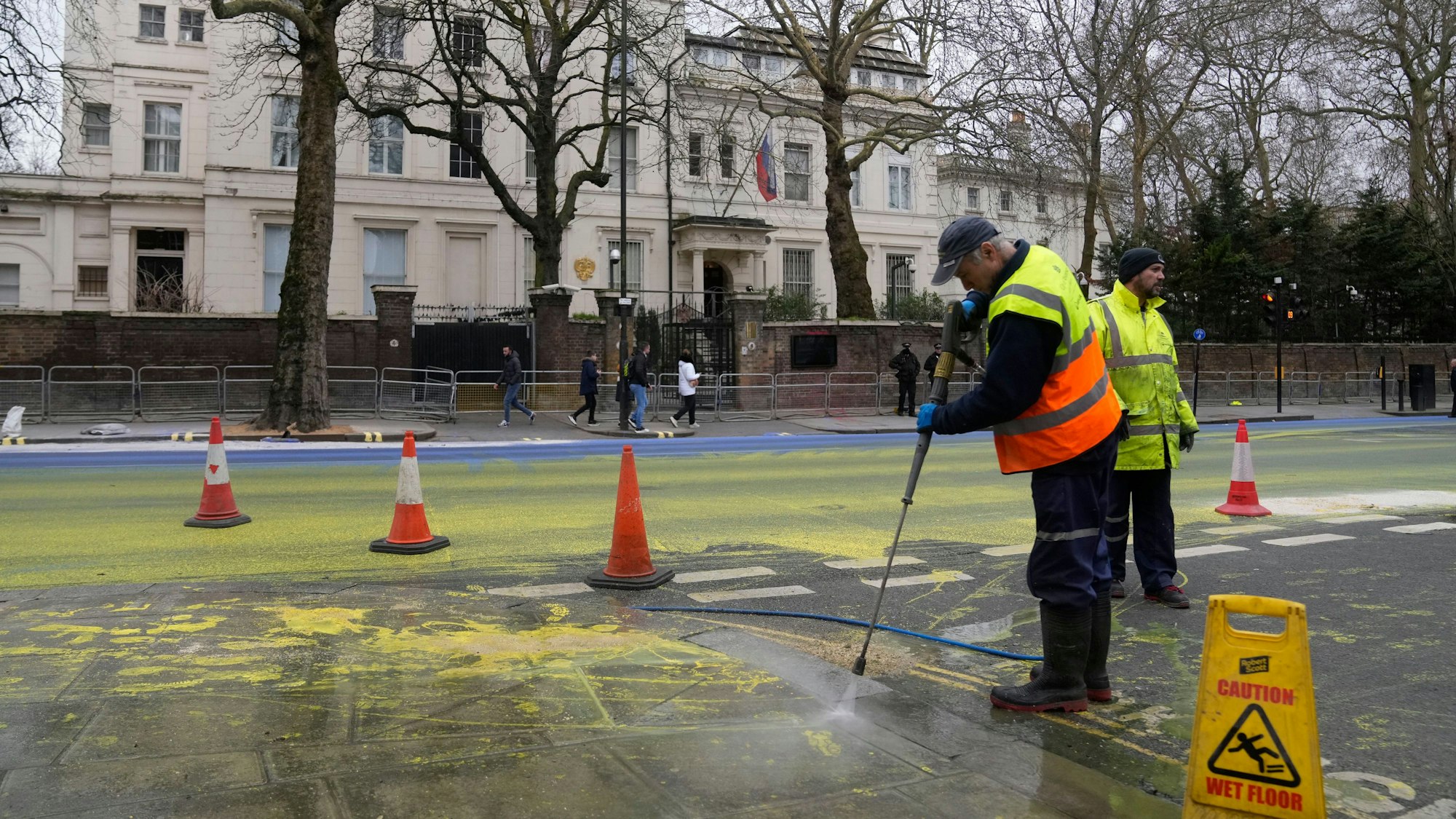 Anti-Kriegs-Aktion: Mitarbeiter der Straßenreinigung entfernen die blaue und gelbe Farbe vor der russischen Botschaft in London.