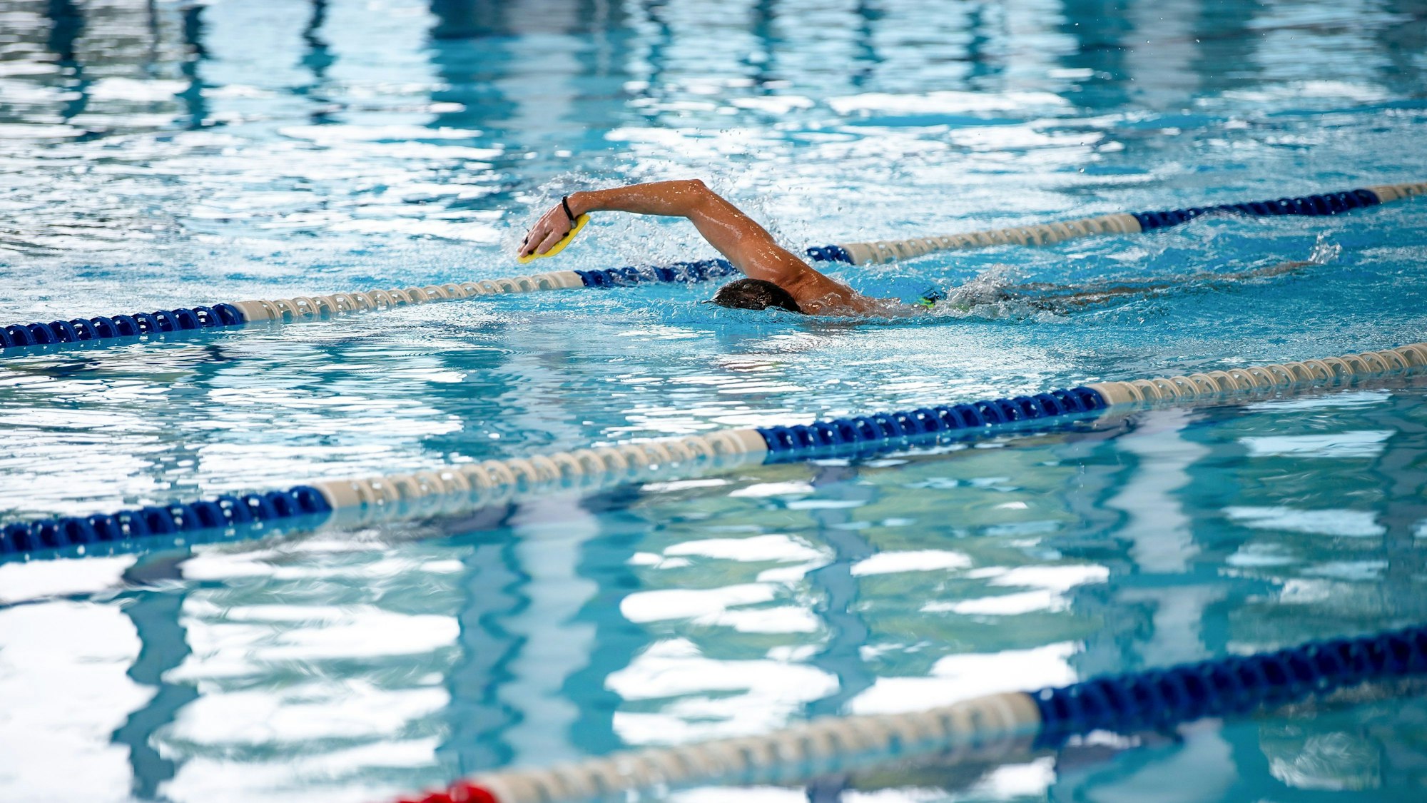 Es ist ein Schwimmbecken zu sehen, indem ein Mensch gerade schwimmt.