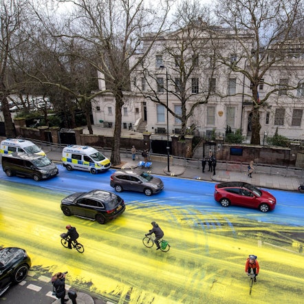London: Fahrradfahrer fahren über eine Straße vor der russischen Botschaft, die von Demonstranten in den Farben der ukrainischen Flagge angemalt wurde.