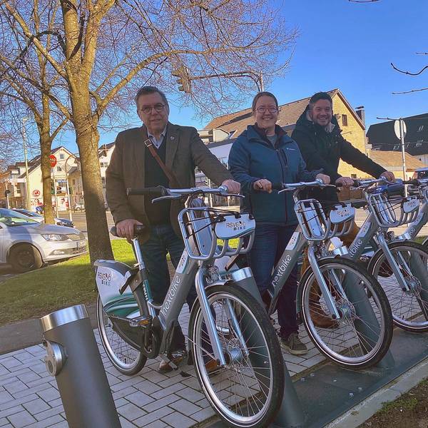Drei Personen stehen jeweils mit einem E-Bike an der Station.