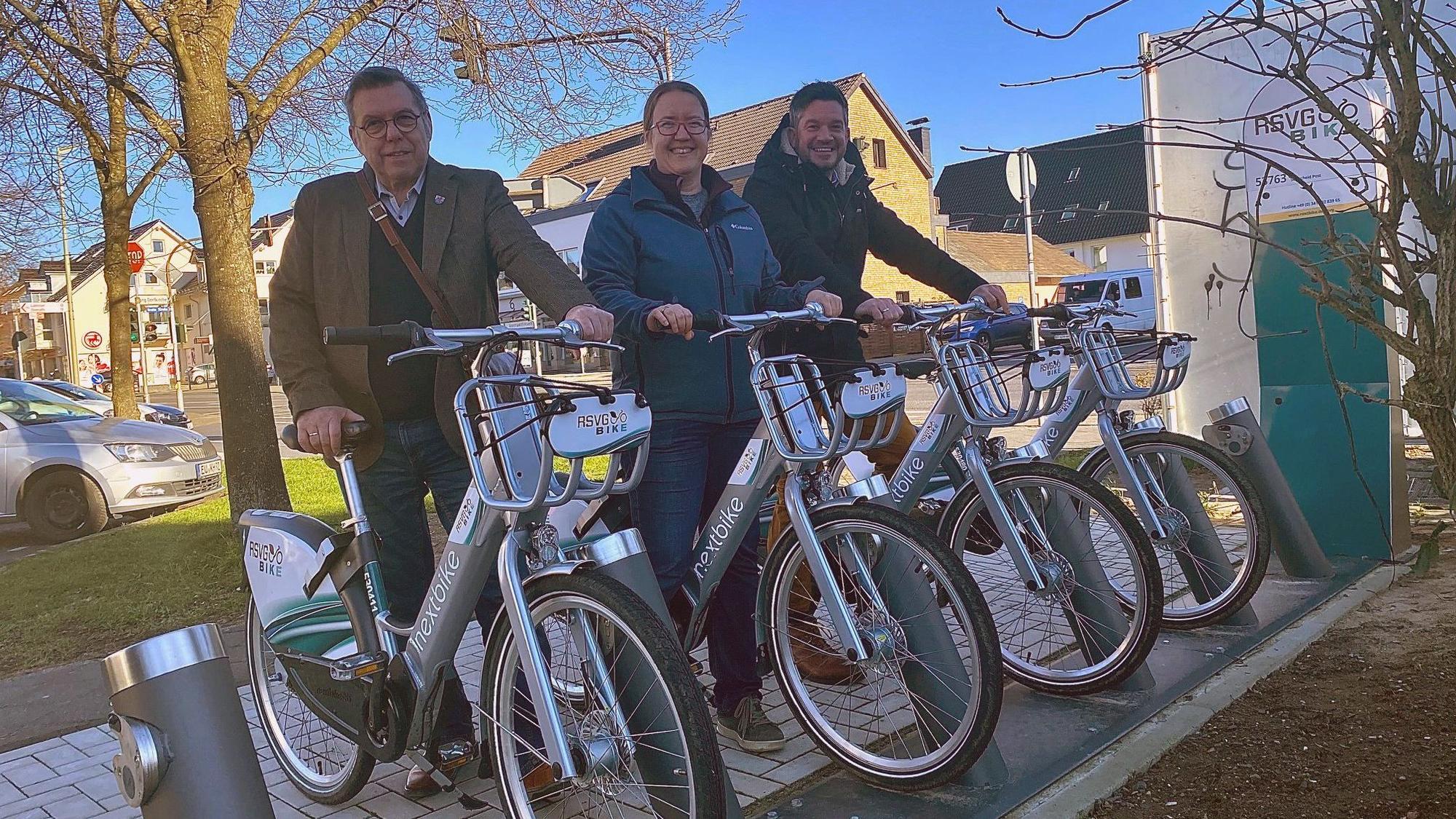 Drei Personen stehen jeweils mit einem E-Bike an der Station.