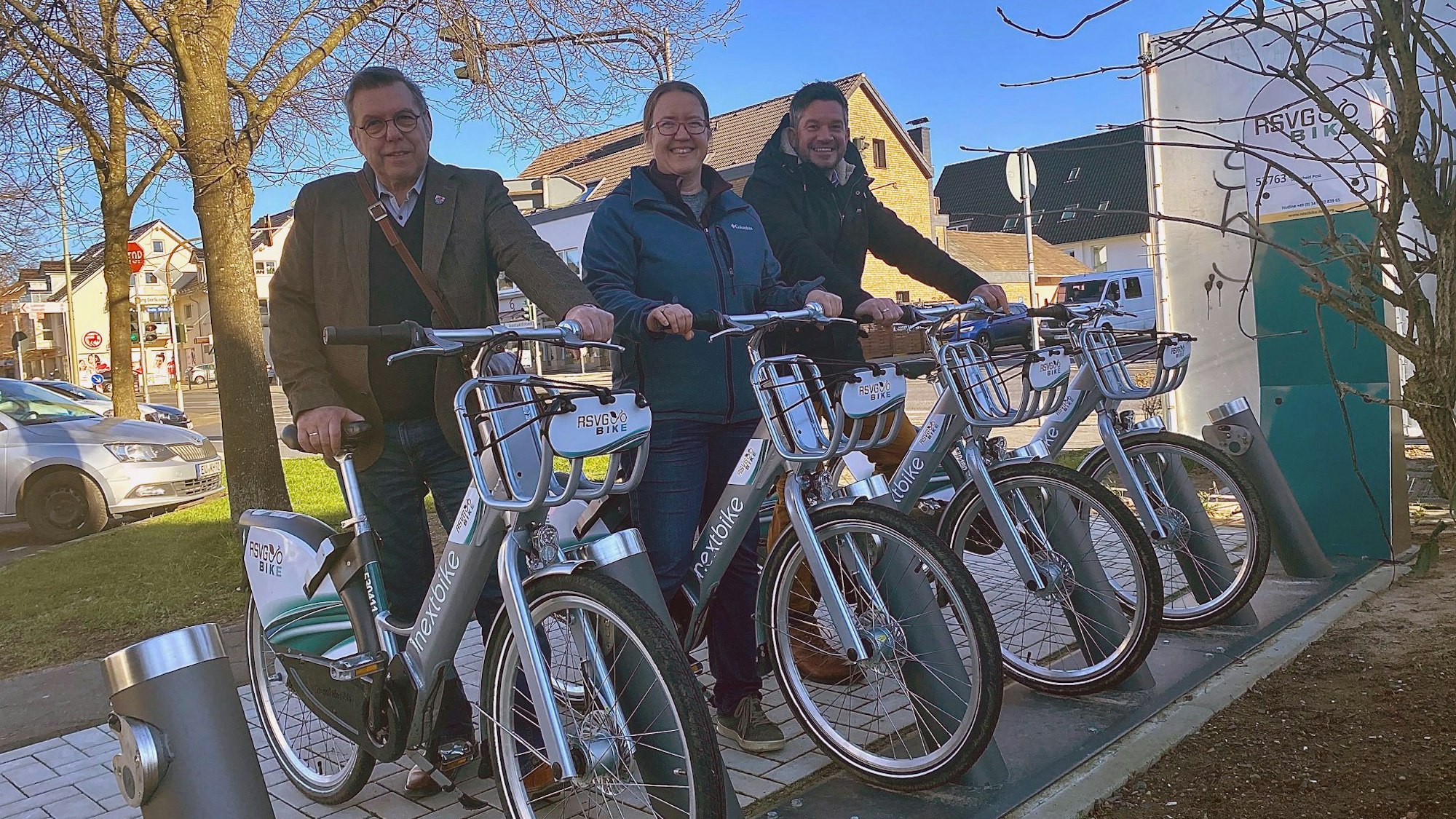 Drei Personen stehen jeweils mit einem E-Bike an der Station.