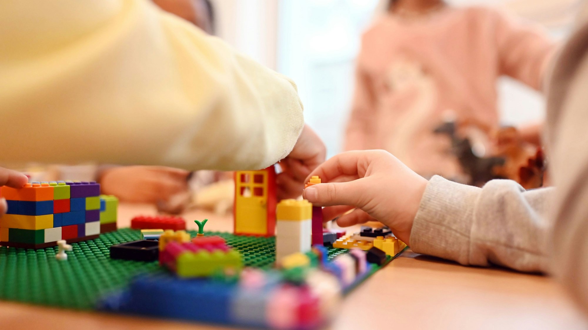 Es sind mehrere Kinderhände zu sehen, die mit Bausteinen bauen.