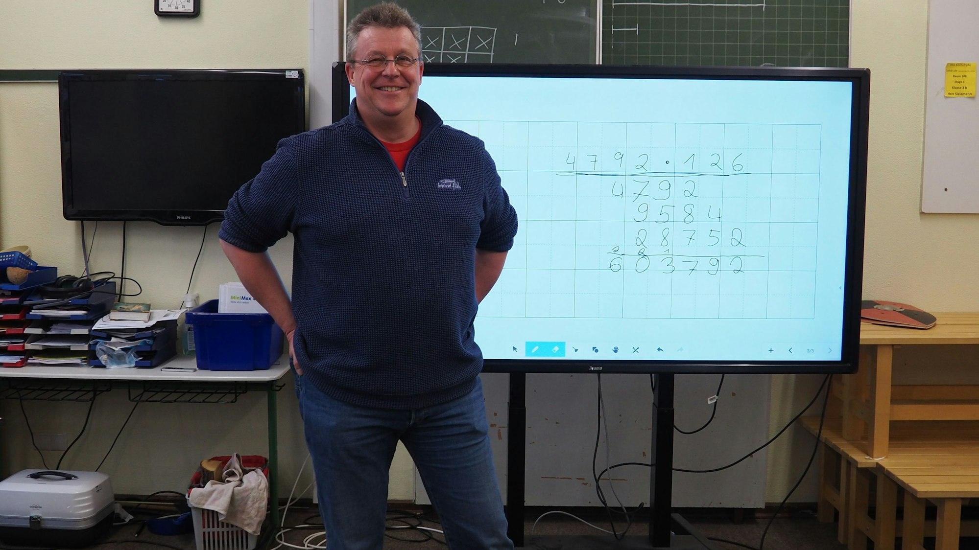 Lehrer Bernd Sielemann in seinem Klassenzimmer vor einer digitalen Tafel