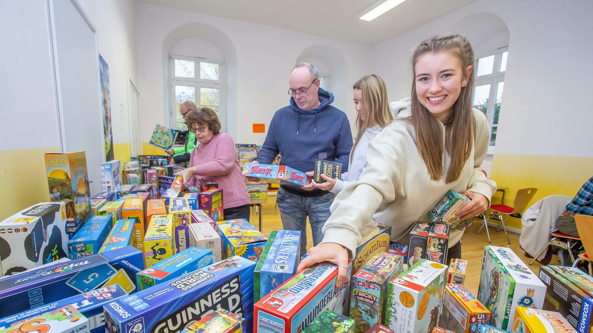 Es sind mehrere Menschen zu sehen die sich Brettspiele anschauen.