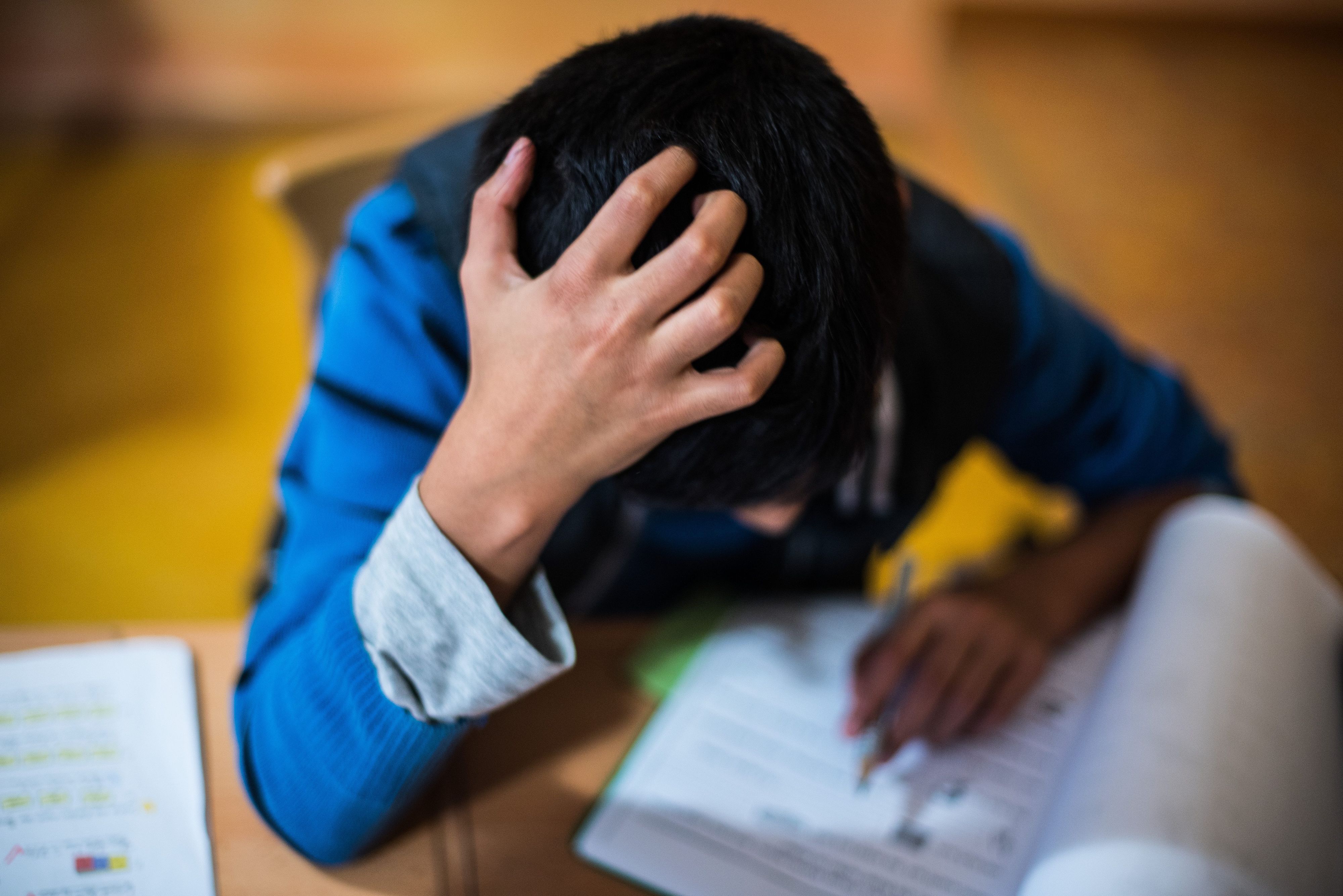 Ein Junge sitzt grübelnd in der Hausaufgabenhilfe an seinen Schularbeiten. Die Kindergrundsicherung ist im Koalitionsvertrag vereinbart worden.