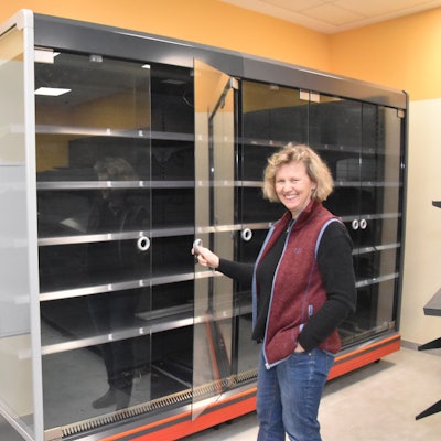 Zwei Personen stehen vor einem Warenregal, das noch leer ist. Ute Klein lächelt in die Kamera.