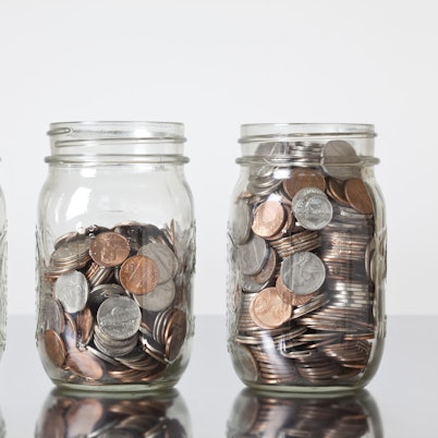 Drei Krüge gefüllt mit Münzen stehen auf einem Tisch.