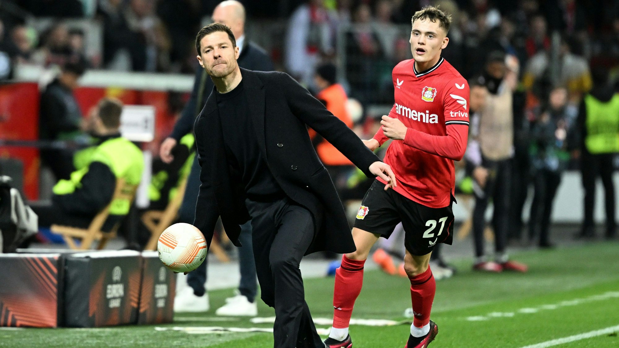 Leverkusens Trainer Xabier Alonso wirft neben Florian Wirtz einen Ball.