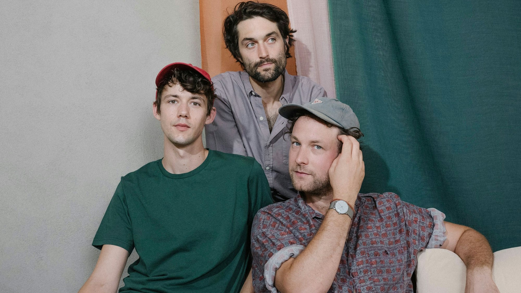 Drei junge Männer sitzen auf dem Sofa