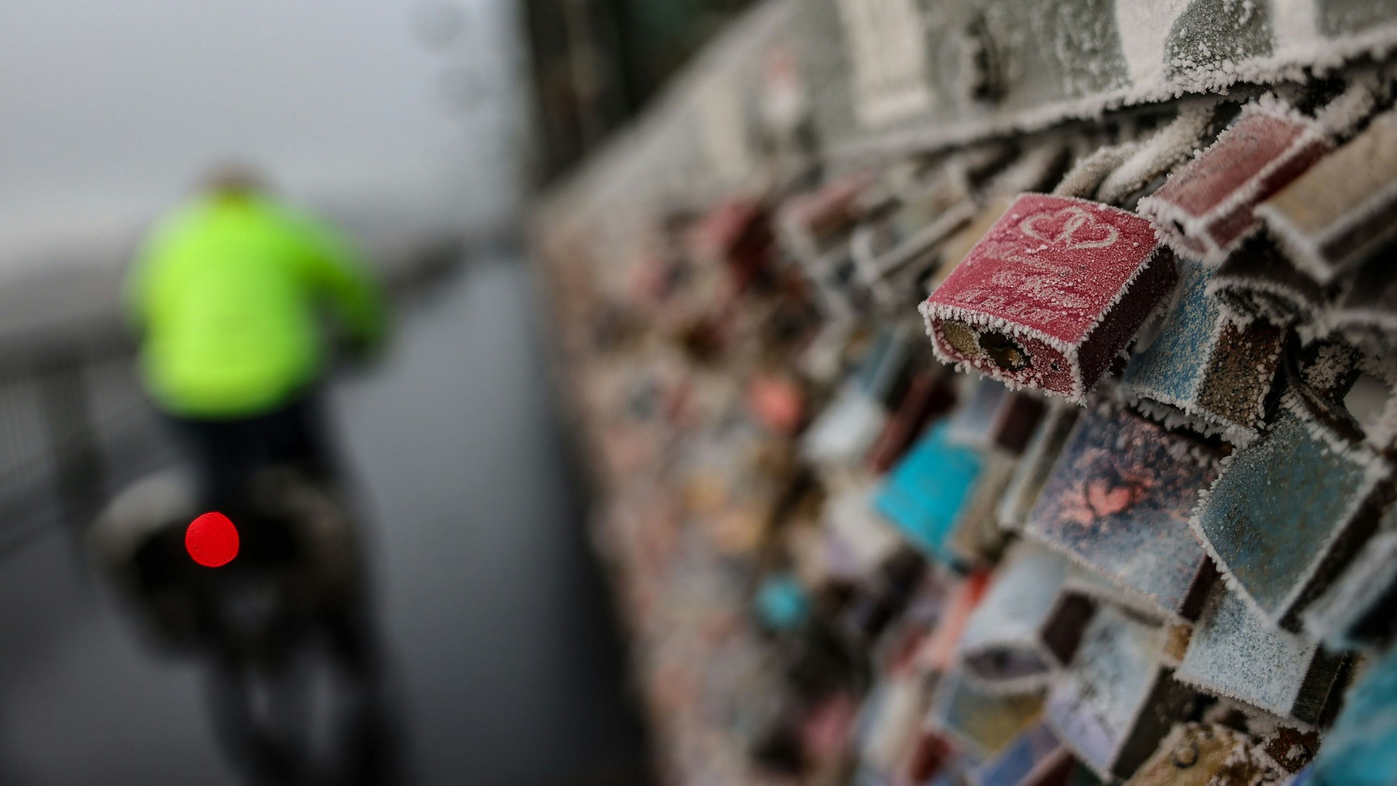 Liebesschlösser an der Hohenzollernbrücke sind im Morgennebel mit Raureif überzogen.