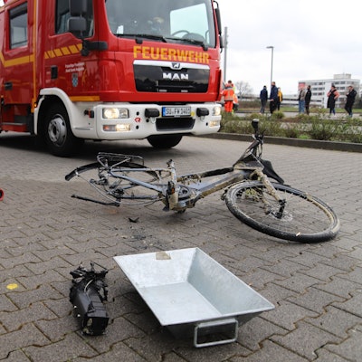 Ein kaputtes Pedelec liegt vor einem Einsatzwagen der Feuerwehr.